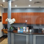 Gray reception desk with wood cabinetry, white orchid, and organized workspace