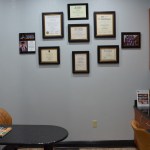 Wall display of framed professional certificates, diplomas, and credentials