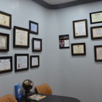 Wall display of framed professional certificates, diplomas, and credentials