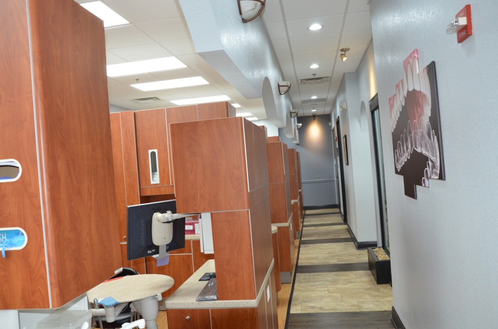 Long corridor with wooden privacy dividers separating dental treatment areas and operatories