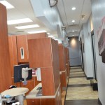 Long corridor with wooden privacy dividers separating dental treatment areas and operatories