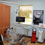 Dental treatment operatory with patient chair, computer monitor, equipment, and wooden privacy panels
