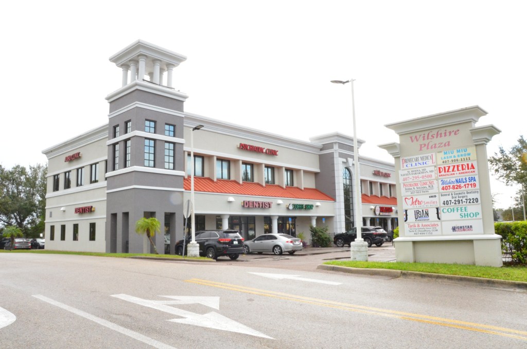 Modern multi-story medical/dental office building with white and gray architecture, tower features, and parking area