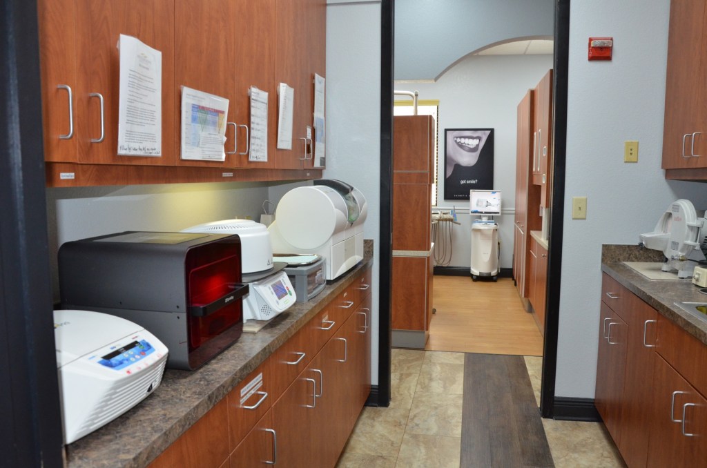 Dental laboratory sterilization area with wooden cabinets, countertops, and autoclave equipment