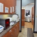 Dental laboratory sterilization area with wooden cabinets, countertops, and autoclave equipment