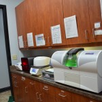 Dental lab workspace with wooden cabinetry and CAD/CAM milling machine for restorations