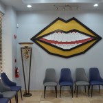 Modern dental office waiting room with blue chairs, decorative lip artwork on wall, and contemporary design