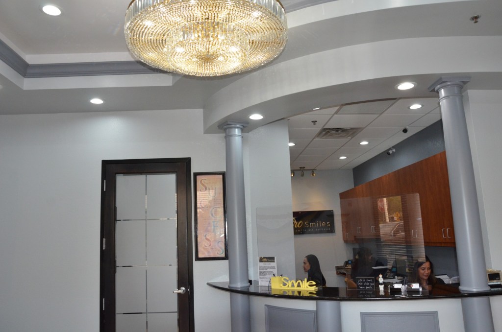 Elegant reception area with crystal chandelier, modern interior design, and curved architectural elements in dental office