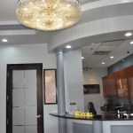 Elegant reception area with crystal chandelier, modern interior design, and curved architectural elements in dental office