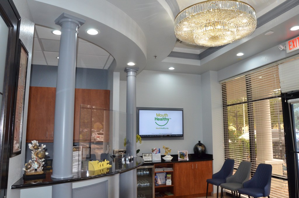 Elegant dental office reception with crystal chandelier, modern decor, and seating area