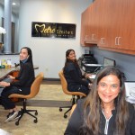 Three female staff members at administrative workstations with computers and Metro Smiles signage